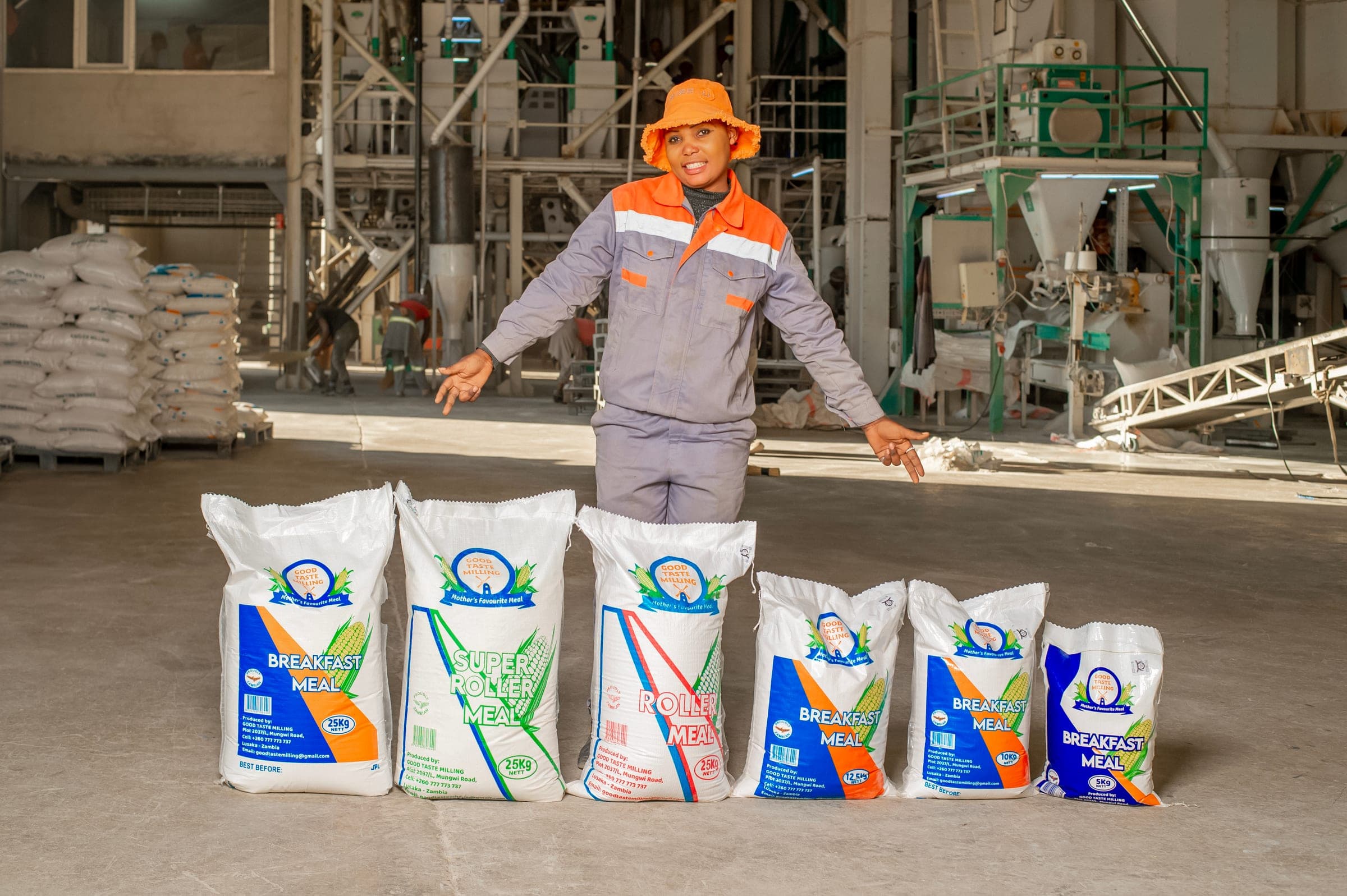 The full range of Good Taste Milling meal sacks lined up from 25 kg down to 5 kg, with a member of staff behind them